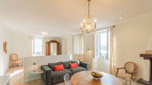 Ein modernes Wohnzimmer mit einem grauen Sofa, roten Kissen, einem Holzesstisch und einer Chandelier.