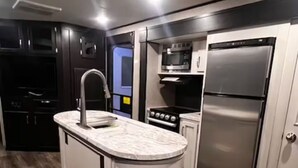 A modern kitchen with a central island, built-in oven, microwave, and stainless steel refrigerator. - Private Adirondack Family Retreat. (Moriah)