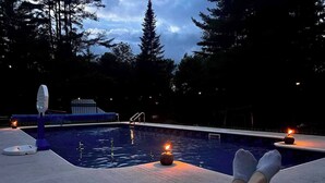 A poolside area with a pool, lounge chairs, and candles. - Private Adirondack Family Retreat. (Moriah)