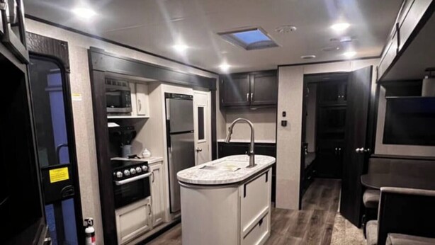 A compact kitchen with a central island, built-in appliances, and a small seating area. - Private Adirondack Family Retreat. (Moriah)