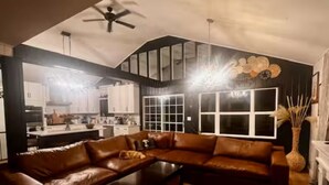 A modern living room with a brown leather sectional sofa, a coffee table, and a large window. - Private Adirondack Family Retreat. (Moriah)
