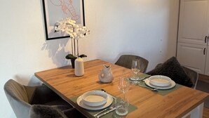 A dining area with a wooden table, white plates, and a vase of white flowers.