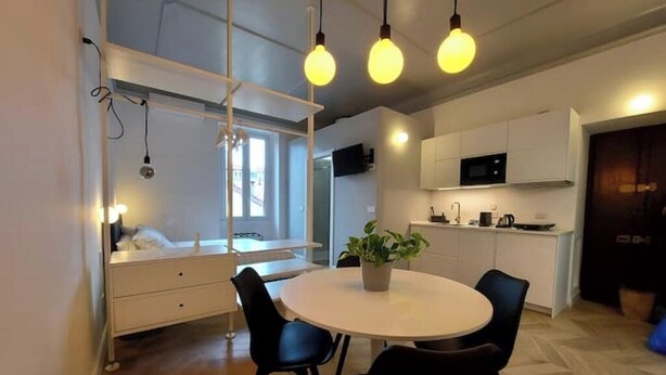 Une cuisine moderne avec des meubles blancs, un four à micro-ondes et un coin repas comprenant une table ronde et des chaises.