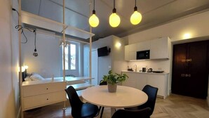 Une cuisine moderne avec des meubles blancs, un four à micro-ondes et un coin repas comprenant une table ronde et des chaises.