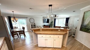 A spacious kitchen with a large island, wooden cabinets, and a dining area with a table and chairs. - Beachside Gem Steps from Intracoastal (St. Augustine)