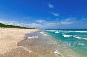 A beach with clear blue water, a sandy shore, and a distant horizon. - Beachside Gem Steps from Intracoastal (St. Augustine)