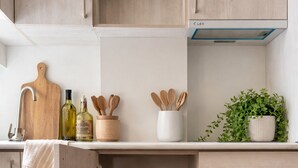 Eine Küche mit Holzausstattung, einer Arbeitsplatte mit Schneidebrett, Flaschen, Holzlöffeln, einer Pflanze und einer Dunstabzugshaube.