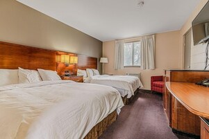 Una habitación de hotel con dos camas, un escritorio, una silla, un televisor y una ventana con cortinas.