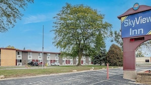 Skilt for SkyView Inn med et godt overblik over motellets facade, herunder en parkeringsplads og et stort træ i forgrunden.