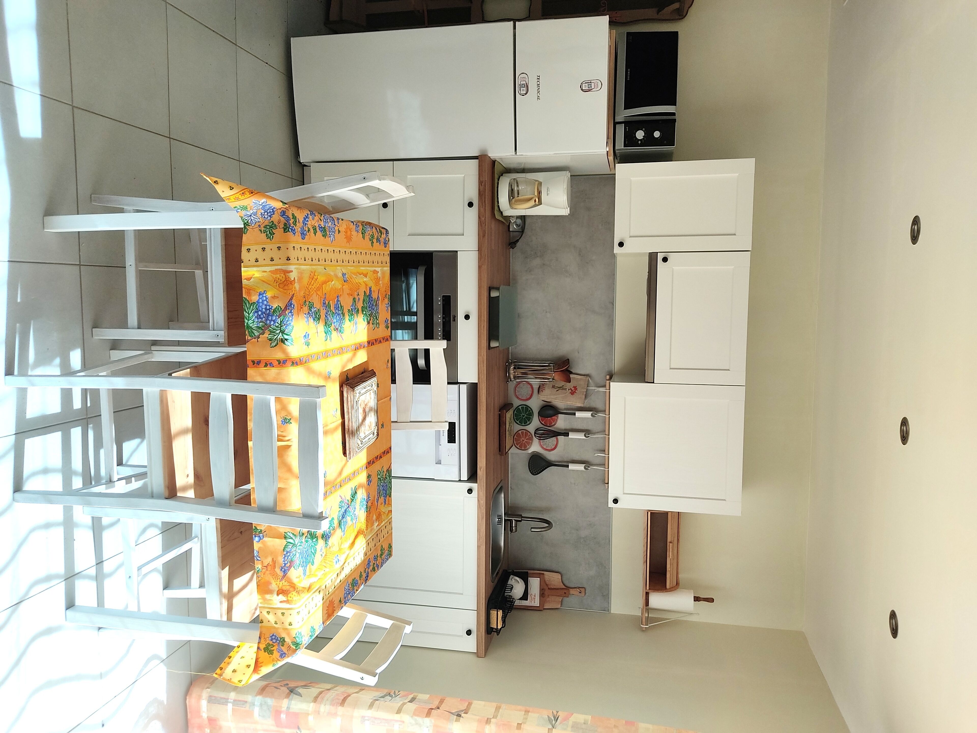 Una cocina compacta con armarios blancos, microondas y cafetera.