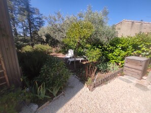 A garden with a gravel path, white chairs, and a wooden shed. - Rent F1 in Luberon near 30 km from Aix en Provence, Cavaillon, (Cadenet)