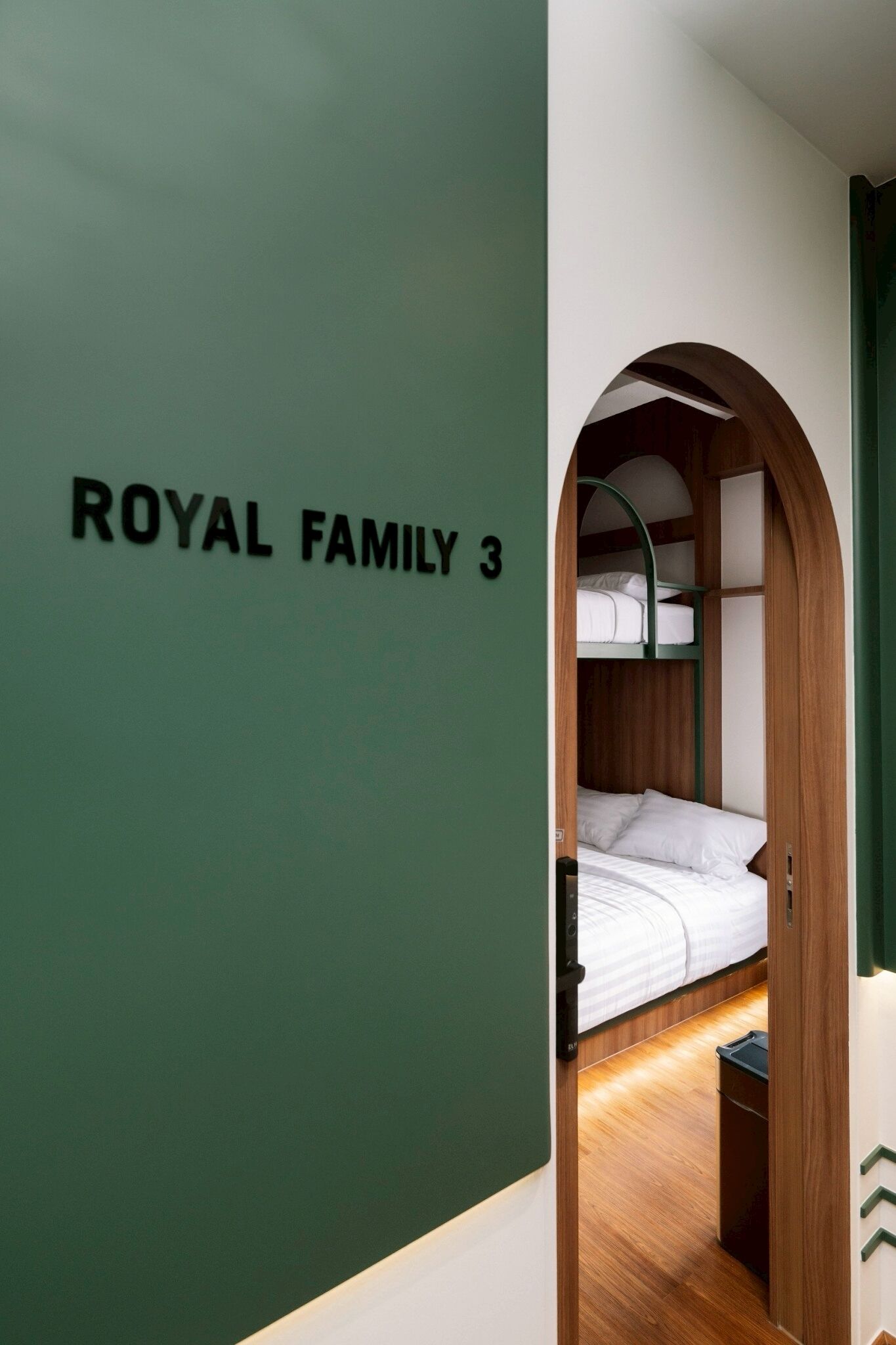 A room labeled 'ROYAL FAMILY 3' with a bunk bed, a small trash bin, and a green wall.