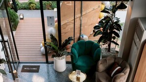 Un intérieur moderne avec un canapé vert, un fauteuil vert et un canapé marron. On y trouve un paillasson et une plante en pot.