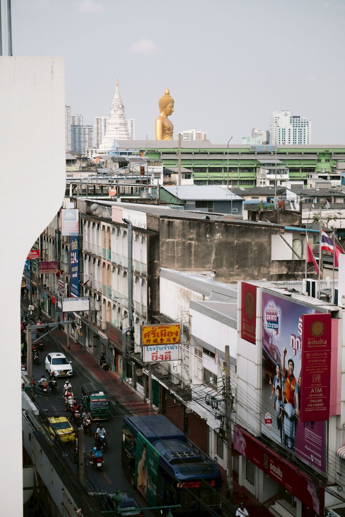 A busy urban street with a large golden statue in the background.