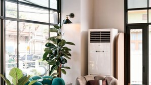 Un salon moderne doté d’une grande fenêtre, d’un fauteuil vert, d’un canapé marron et d’une table basse blanche.