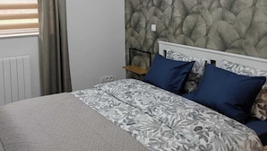 A bedroom with a patterned bedspread, a headboard with a leaf-like design, and a radiator. - Stork country (Brugelette)