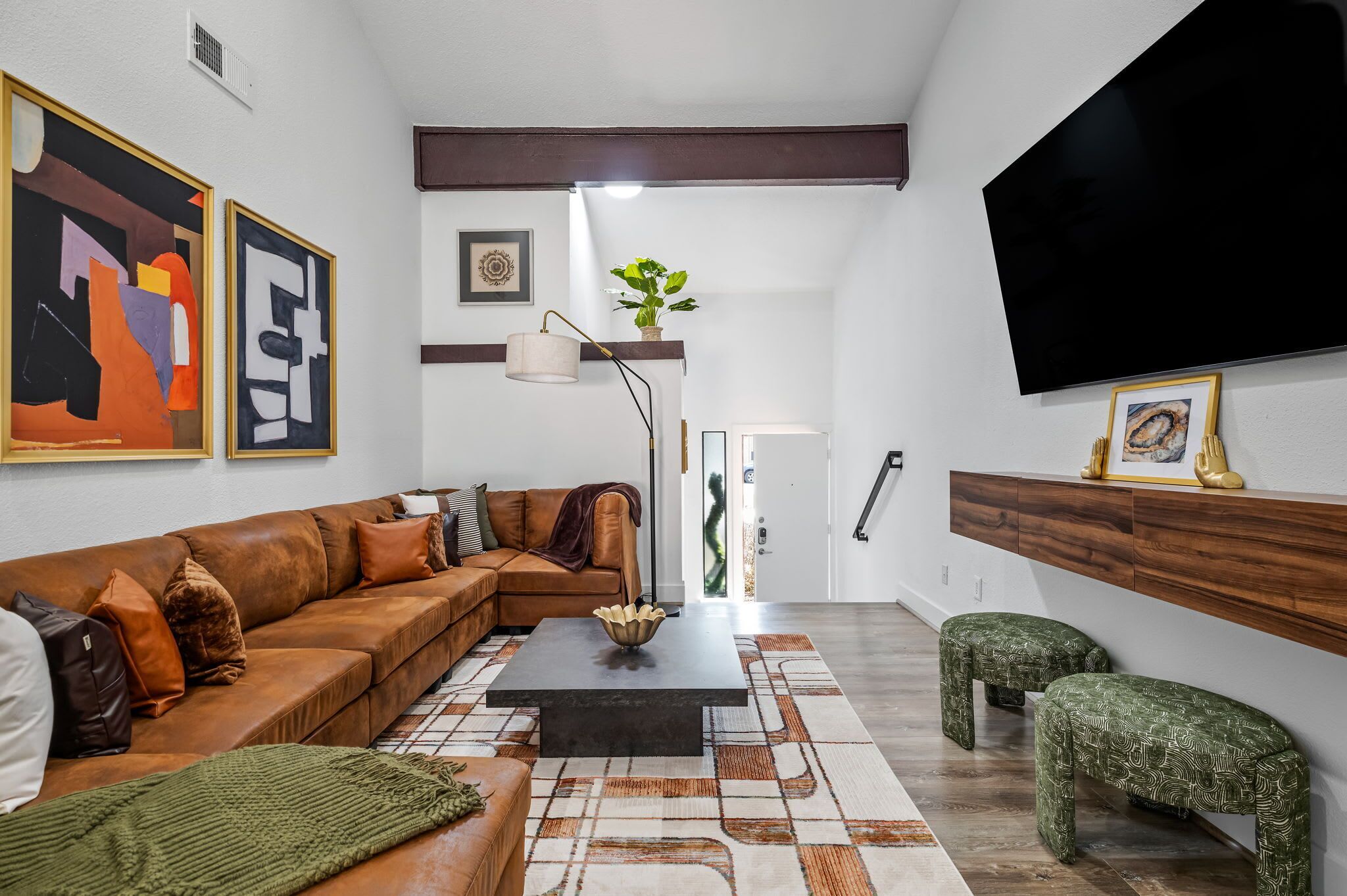 Un salon moderne avec un canapé en cuir marron, une table basse noire et un tapis à motifs.