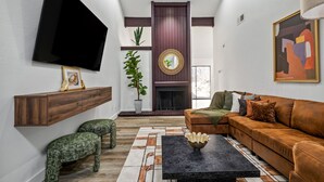 Ein modernes Wohnzimmer mit großem Flachbildfernseher, Kamin, Sofa und Couchtisch.