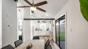Un comedor moderno con una mesa de madera, sillas negras y un ventilador de techo.