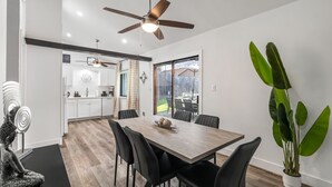 Un comedor con una mesa de madera, sillas negras y un ventilador de techo.