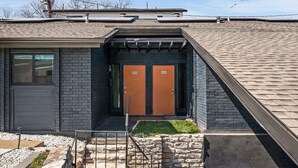 Un edifici modern amb dues portes taronja, façana de rajola i teulat inclinat.
