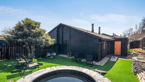 Una casa moderna amb una piscina de pedra, un jardí ben cuidat i una tanca de fusta.