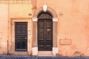 A double door entrance with a number '69' above it, set in a building with a textured wall. - Conduits Loft-city center  (Roma)