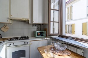 Una cucina con fornello, forno a microonde e finestra che si affaccia su un edificio.