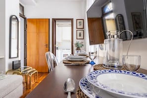 Een eethoek met een houten tafel gedekt voor vier personen, een metalen karaf en een glas.