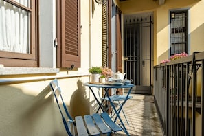 Een balkon met een tafel, stoelen en een bloempot.
