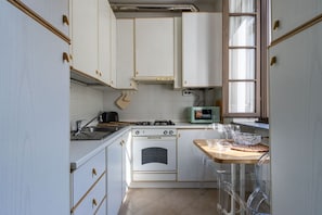 Una cocina con armarios blancos, estufa, microondas y ventana.
