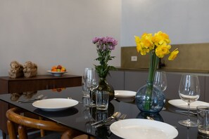 Taula de dinar posta amb plats, coberts i gots, amb un ram de flors al centre.