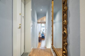 A hallway with a wooden floor, a white door, and a large ornate mirror. - Signoria Design Retreat (Florence)
