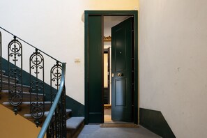 Una escala amb baranes de metall ornamentades que condueix a una porta de color verd fosc.