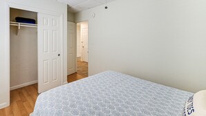 Quarto com cama, armário e corredor que dá para outro cômodo.