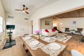 A spacious living area with a dining table set for four, a sofa, and a television. - Legacy Trail Retreat  Bikes, Peloton + Fire Pit (Sarasota)