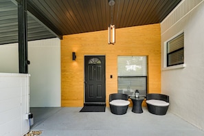 A modern exterior with a black door, wooden paneling, and outdoor seating with cushions. - Legacy Trail Retreat  Bikes, Peloton + Fire Pit (Sarasota)