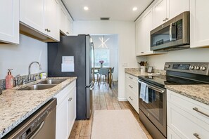 A modern kitchen with granite countertops, stainless steel appliances, and a view into the dining area. - Legacy Trail Retreat  Bikes, Peloton + Fire Pit (Sarasota)