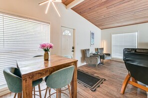 A modern interior with a wooden dining table, two chairs, a black leather sofa, and a small side table. - Legacy Trail Retreat  Bikes, Peloton + Fire Pit (Sarasota)