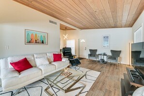 A living room with a white sofa, red cushions, a glass coffee table, and a wooden ceiling. - Legacy Trail Retreat  Bikes, Peloton + Fire Pit (Sarasota)