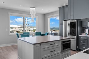 A modern kitchen with a central island, grey cabinetry, and a large window offering a view of a residential area. - Private Pool•Opt Golf Cart•Island Treasure (Navarre)