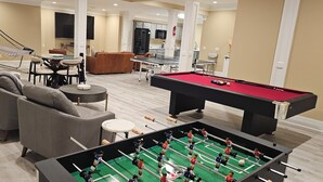 Un ampio soggiorno con tavolo da calcio, tavolo da biliardo e una zona salotto confortevole.