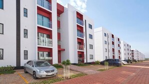A modern apartment building with multiple balconies, a paved driveway, and parked cars. - Sunset Escape Apartment Modern & Spacious Two Bedroom in Tatu City (Ruiru)