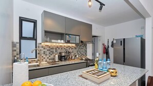 A modern kitchen with a granite countertop, stainless steel appliances, and a tiled backsplash. - Sunset Escape Apartment Modern & Spacious Two Bedroom in Tatu City (Ruiru)