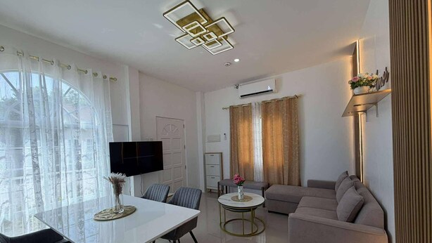 A modern living room with a flat-screen TV, a dining table with chairs, a sofa, and a coffee table. - Casa De Amor Villa 1338 - Panglao (Dauis)