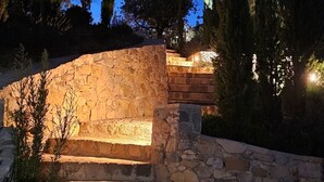 Escalones de piedra que conducen a un muro de piedra con una fuente de luz en la parte superior.