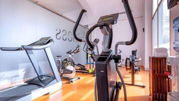Un gimnasio con bicicletas estáticas, cinta de correr y dispensador de agua.