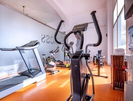 Un gimnasio con bicicletas estáticas, cinta de correr y dispensador de agua.