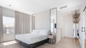 Ein modernes Hotelzimmer mit einem großen Bett, einem Nachttisch, einem Spiegel und Blick auf die Stadt.