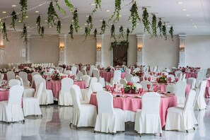 A banquet hall with round tables, white chairs, and pink tablecloths. - Melilla Puerto Hotel (Melilla)